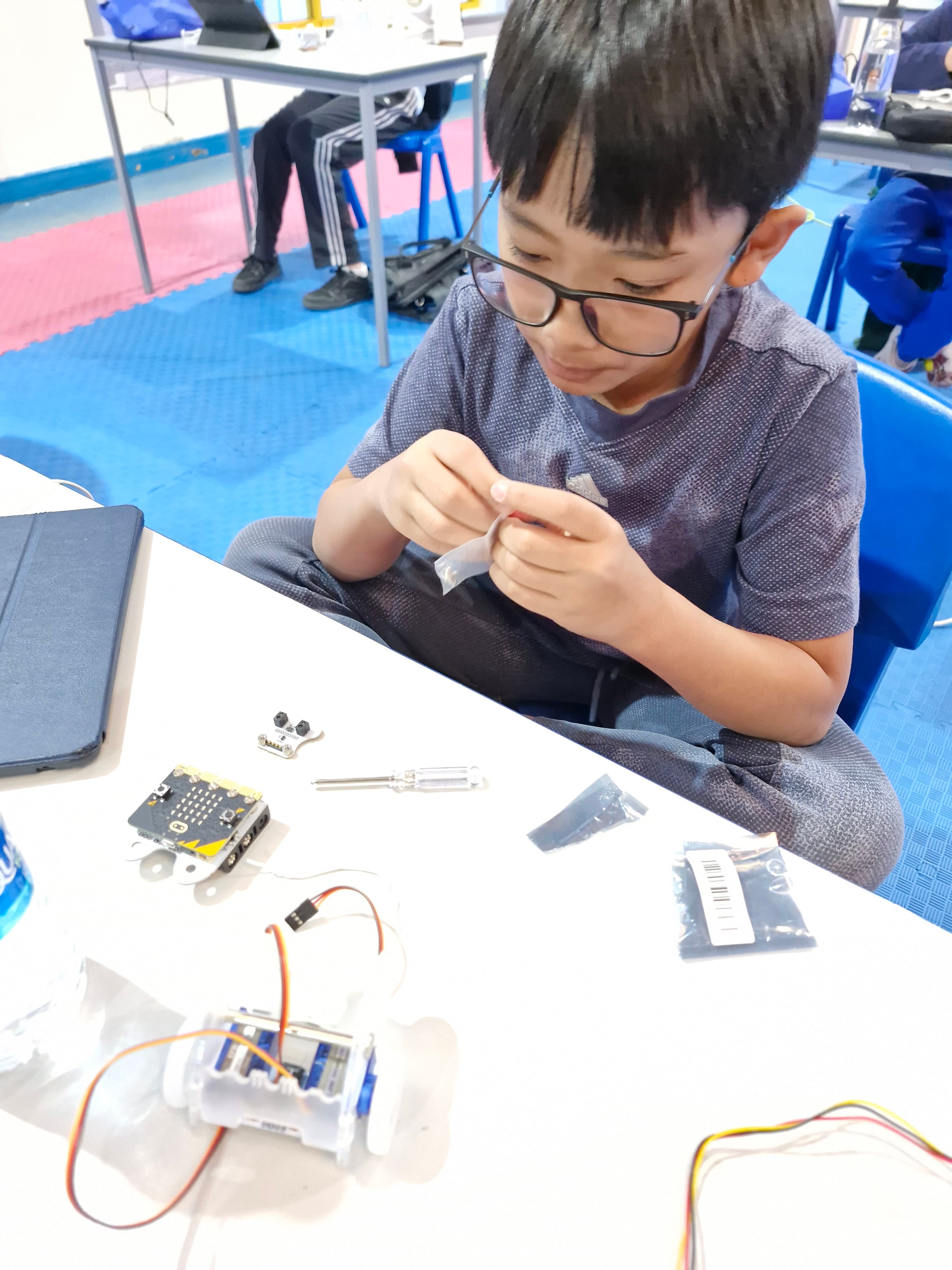 Hands assembling small robot electronics during class