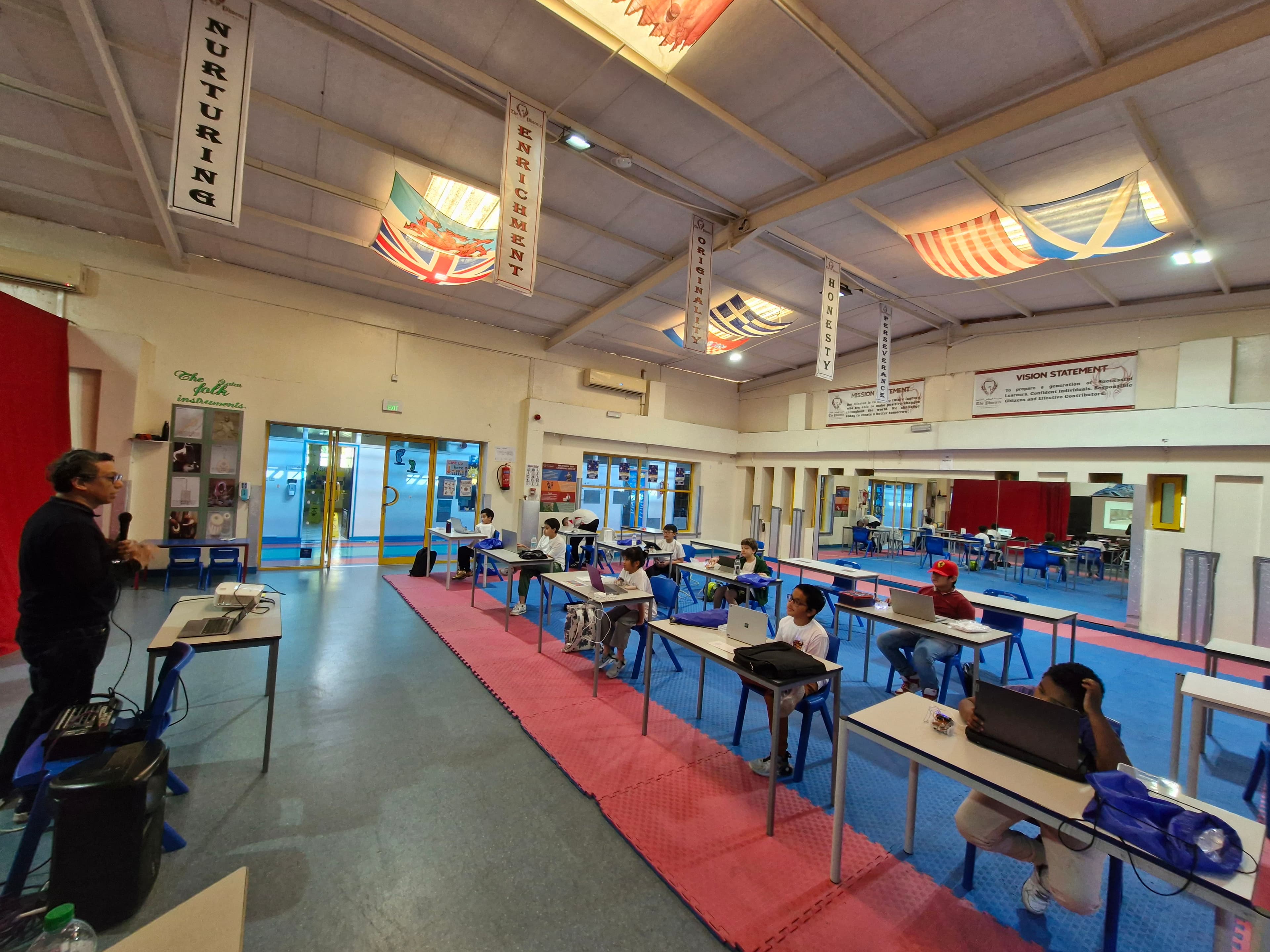 Wide classroom programming session with laptops and robot kits