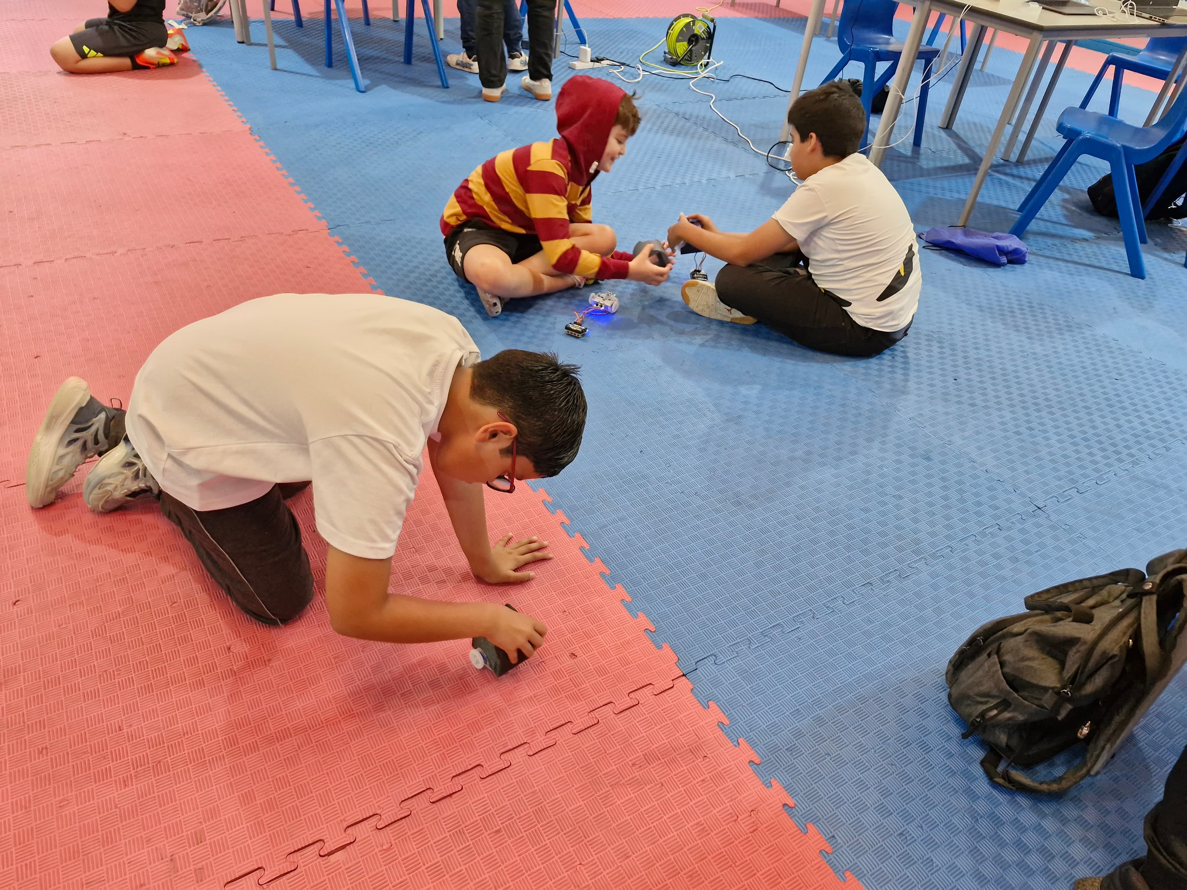 Students testing small robots from an overhead classroom angle